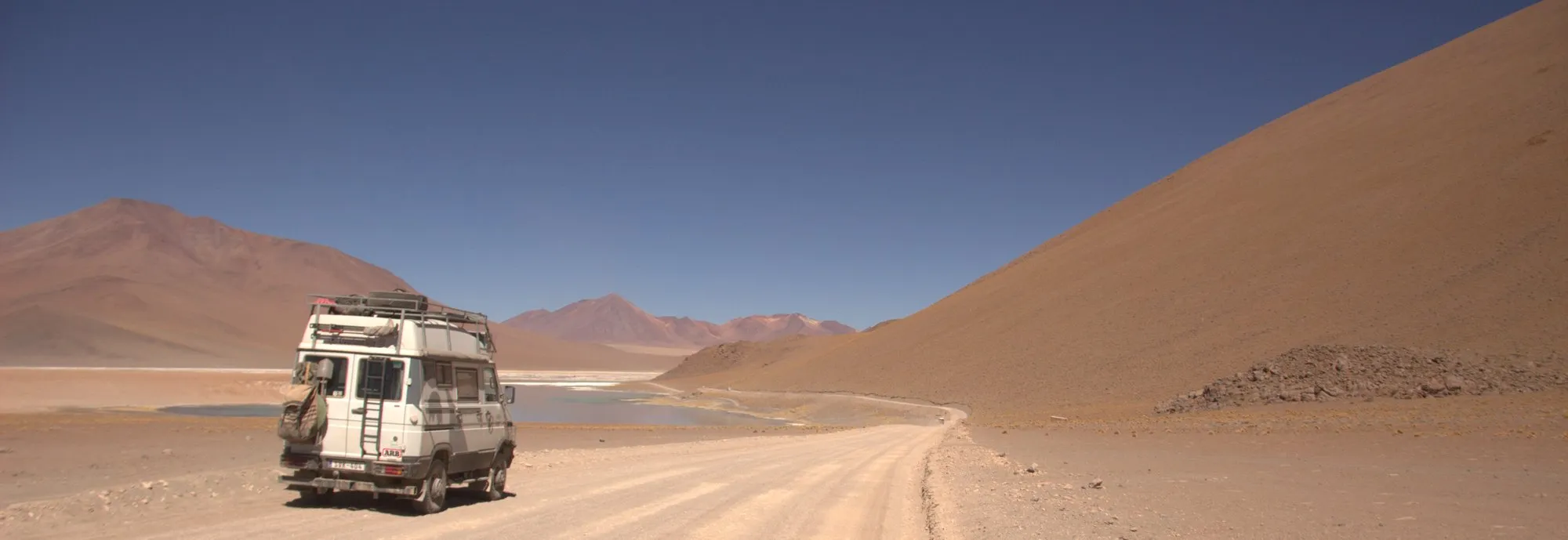 A 4x4 on the altiplano at dusk, dunes rising to the right