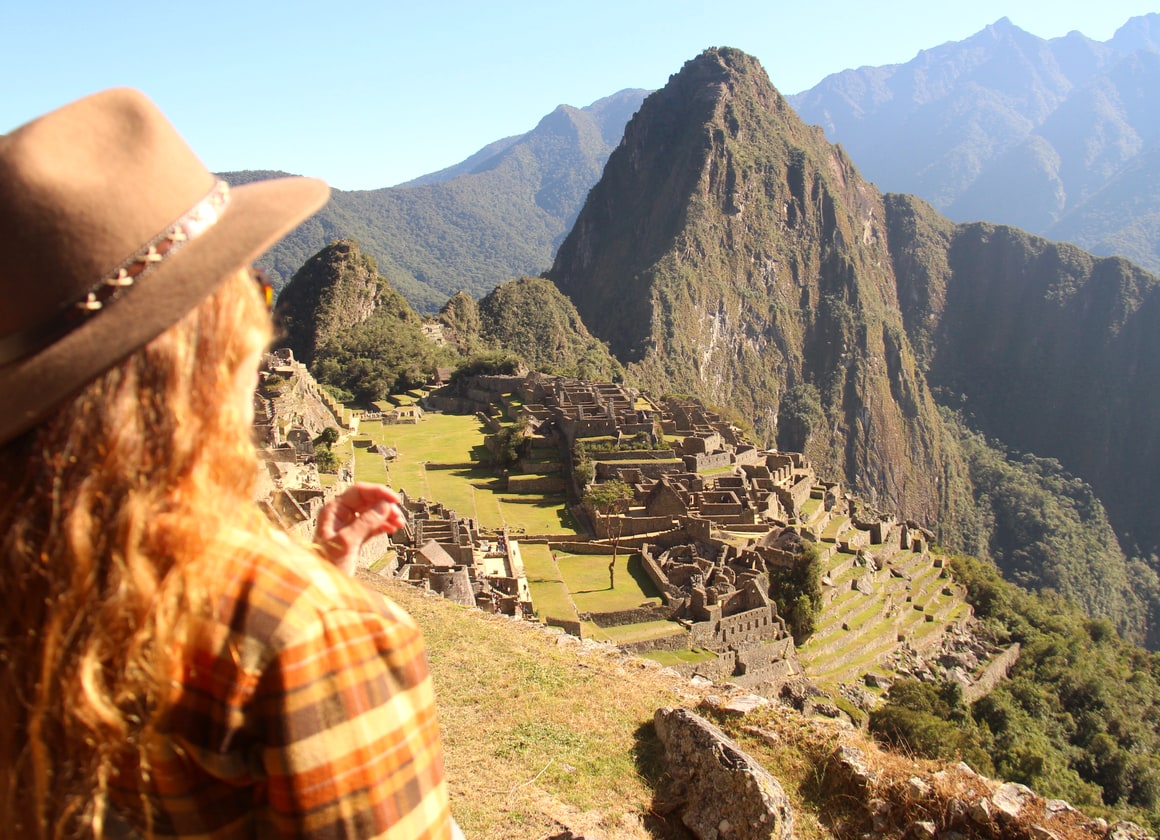 A traveller in a wide-brimmed hat looking out over Machu Picchu