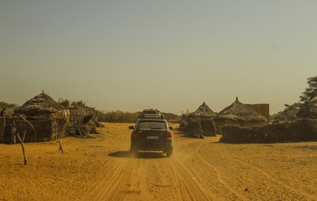 Porsche overlanding through a village in Senegal